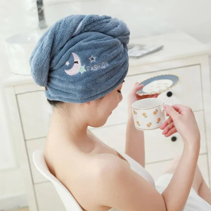 A blue turban-style hair towel worn around gathered hair in a bathroom